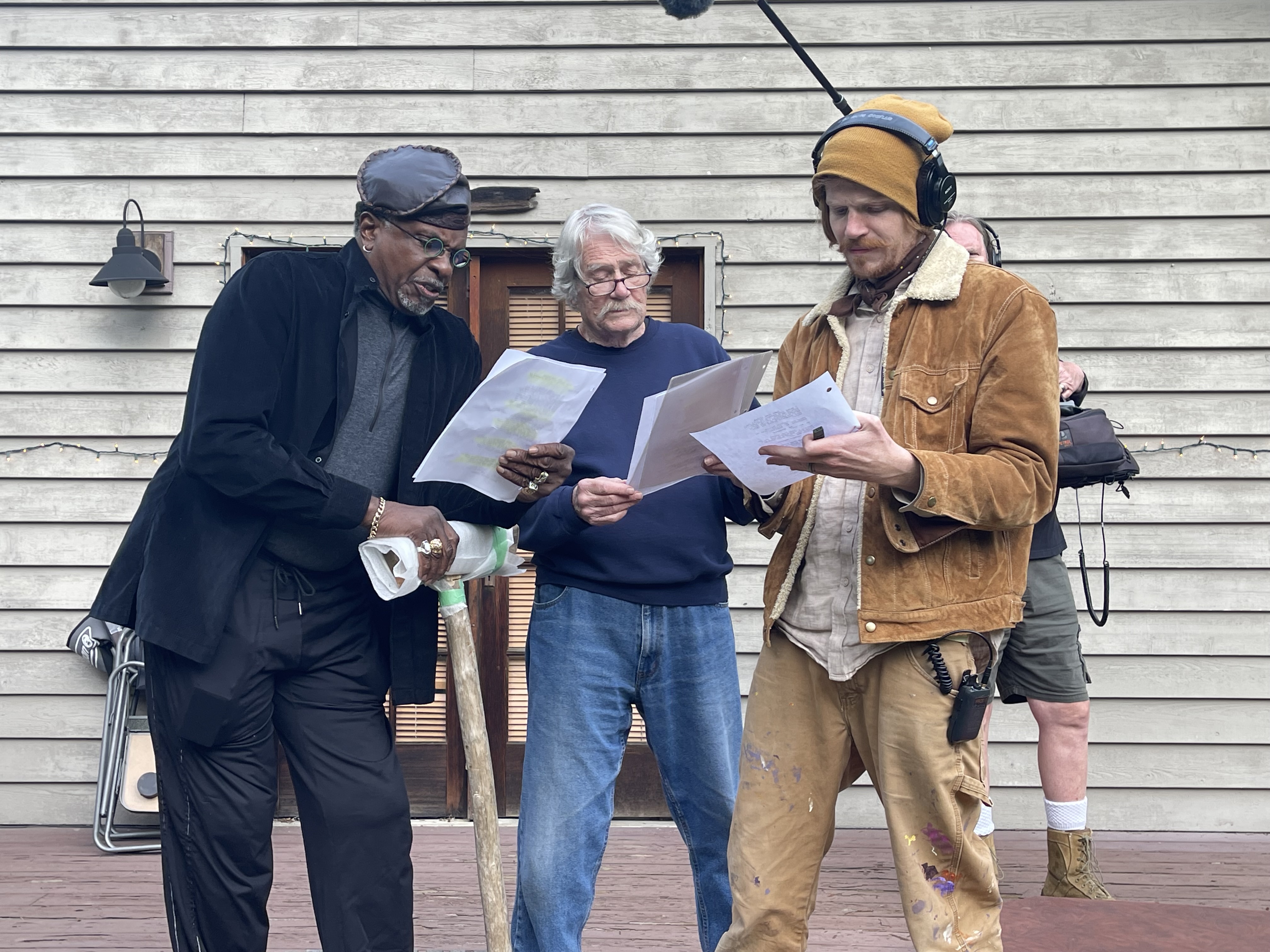Behind the scenes: cast members reviewing scripts outdoors.