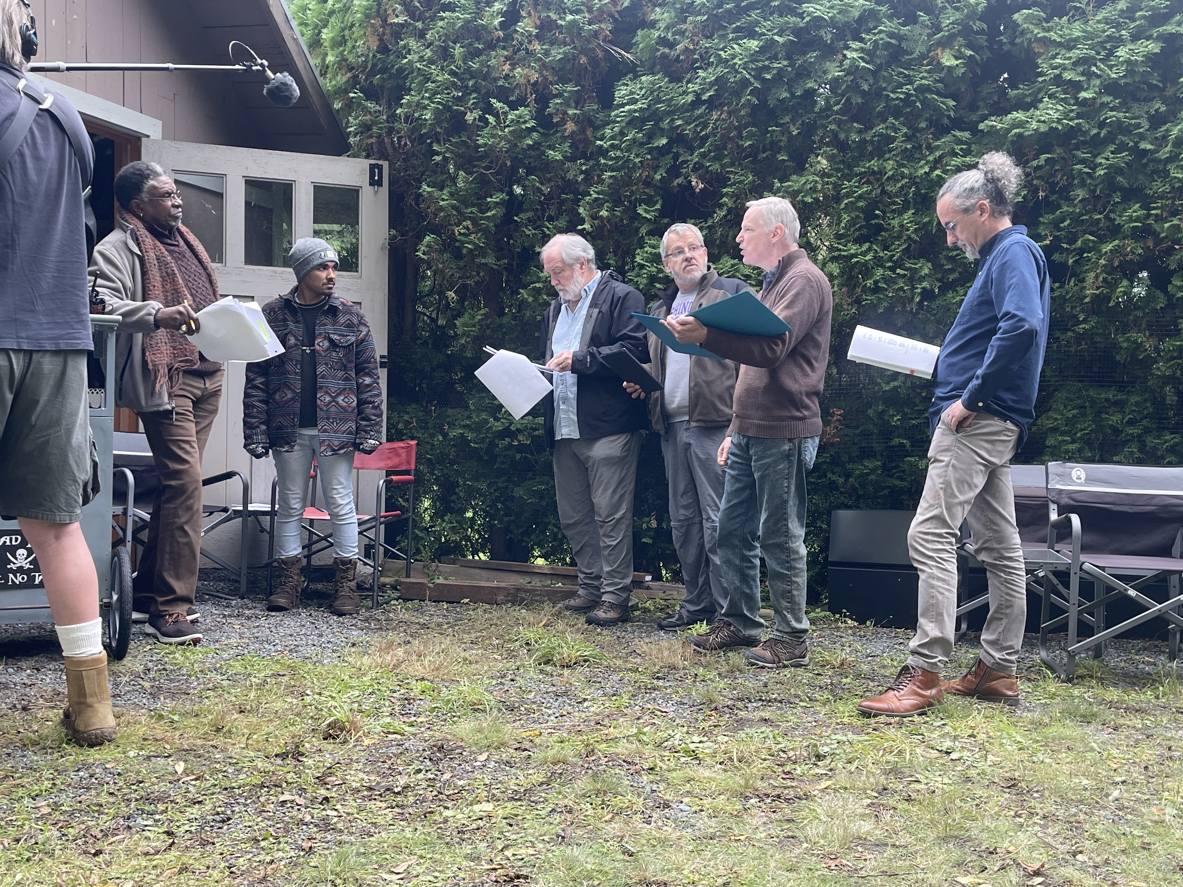 Behind the scenes: cast and crew gathered outside with scripts.